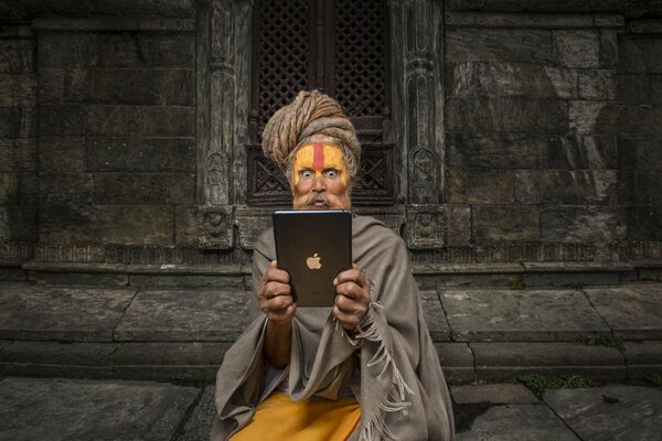 Ein verwunderter Buddhist schaut auf das iPad