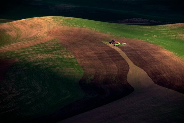 Foto von oben, das Feld, in dem der Traktor arbeitet, Dämmerung