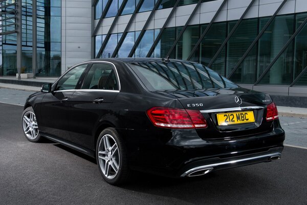 Mercedes-Benzes e 350 schwarz auf der Straße in der Nähe eines Bürogebäudes geparkt