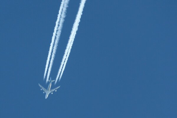 Das Flugzeug fliegt in den blauen Himmel und hinterlässt eine weiße Spur