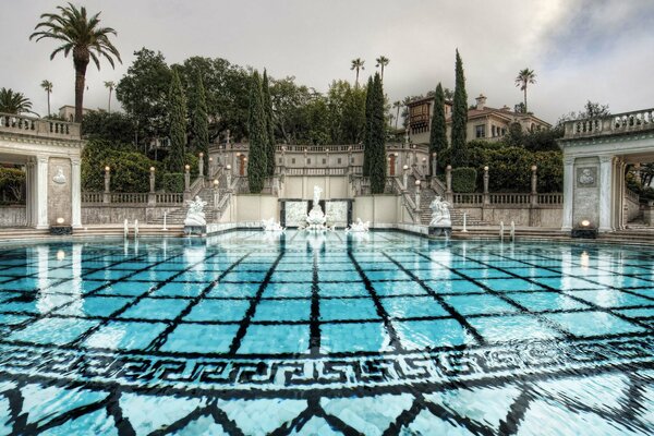 Blaues Schwimmbad am Kurpark mit Treppen und Zypressen