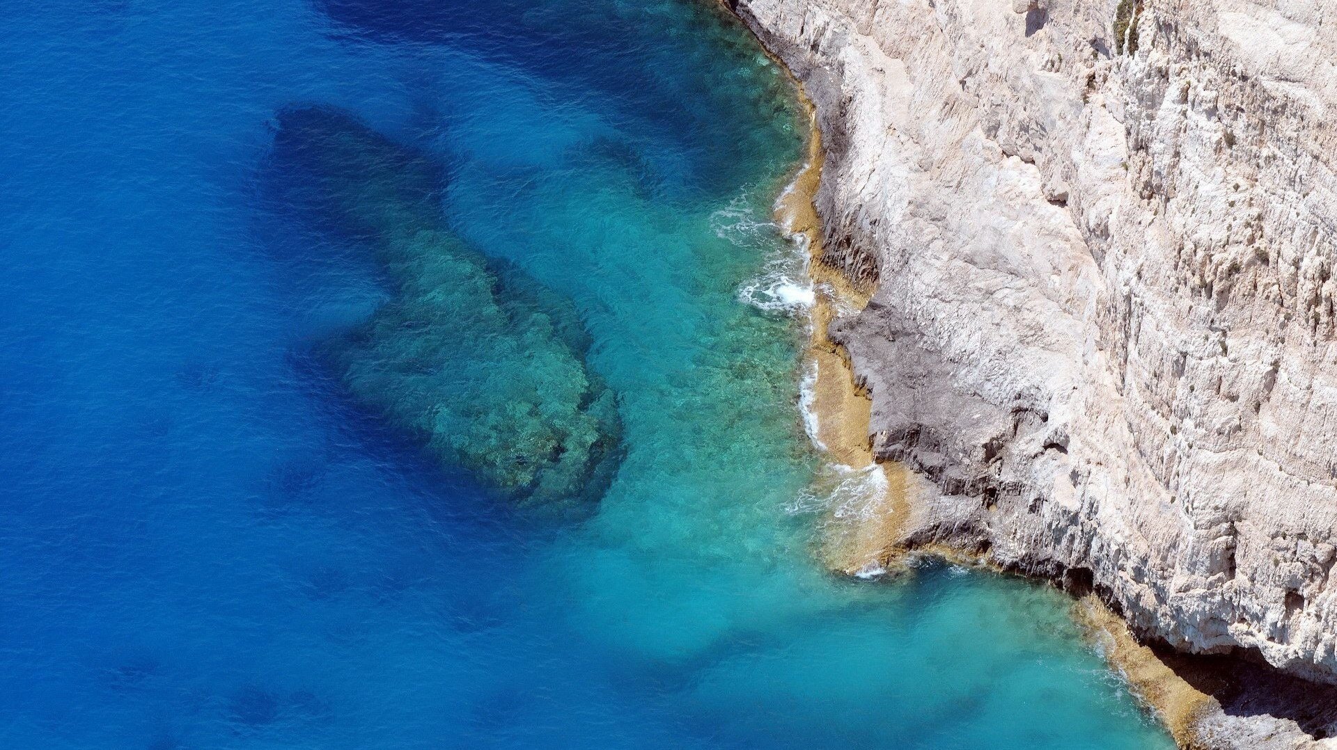 steiler abhang abhang steinfelsen blaues wasser höhe meer boden brandung ufer glatte oberfläche natur aussicht insel steine
