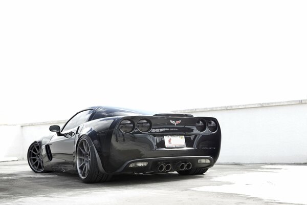 Schwarzes Auto Chevrolet Corvette auf weißem Wandhintergrund