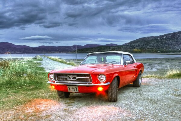 Roter Mustang am See bei bewölktem Wetter