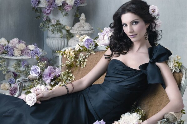 Mädchen im schwarzen Kleid auf einem Hintergrund von Blumen