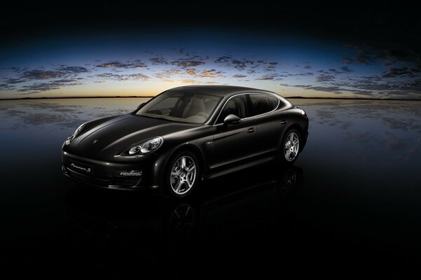 Schwarzer Porsche am Meer bei Sonnenuntergang