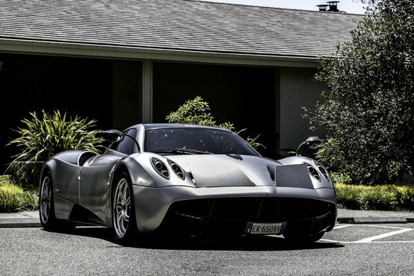 Silberner hübscher pagani huayra auf Hintergrund eines privaten Wohnhauses