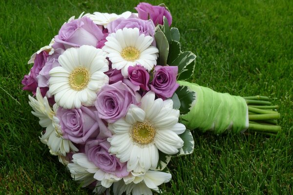 Ein Blumenstrauß mit Kamille und Rosen liegt auf dem Rasen