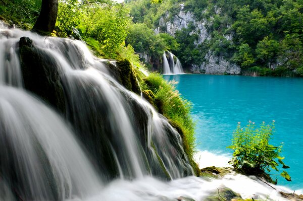 Ein Bergfall, der in einen blauen See mündet