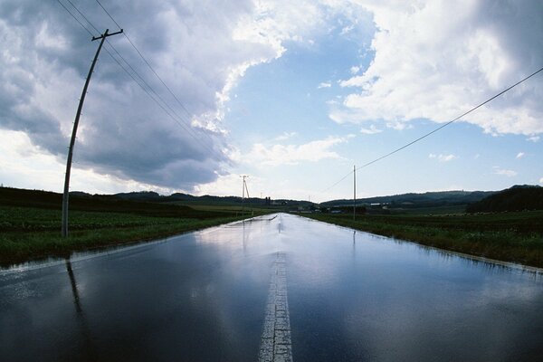 Die Straße, die zum Horizont führt, mit Säulen an den Straßenrändern und einem Himmel mit großen Wolken