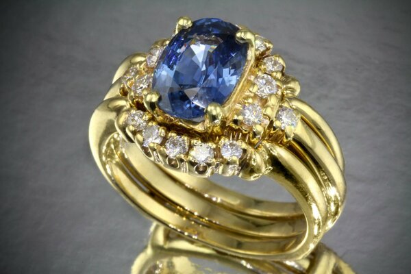 Goldener Ring mit einem großen blauen Stein und einer Streuung von Diamanten