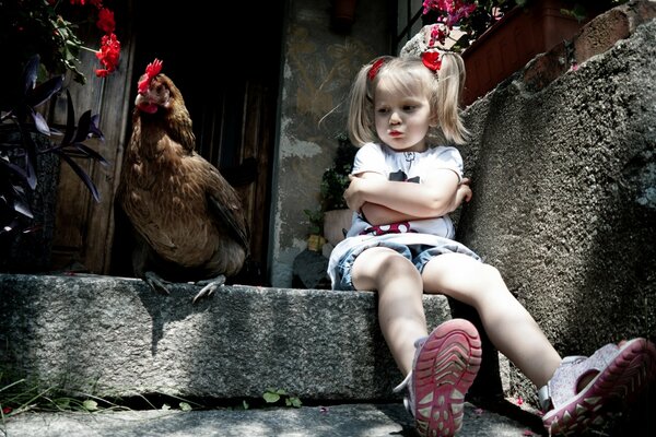 Foto von einem beleidigten Mädchen und einem Huhn auf der Veranda