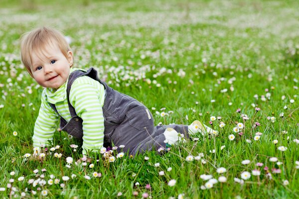 Glückliches Kind sitzt im Gras mit Blumen