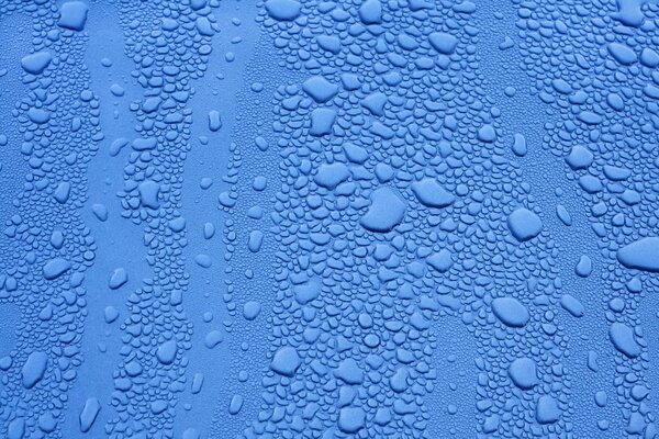 Tropfen unterschiedlicher Größe auf blauer Oberfläche