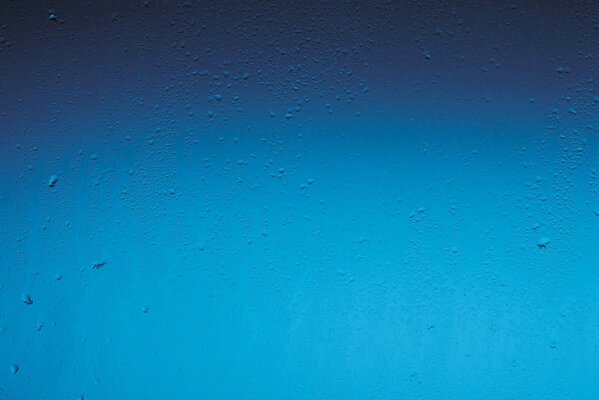Regentropfen auf blauem Fensterhintergrund