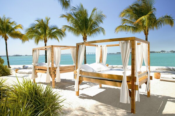 Sonniger Strand mit Betten unter Palmen