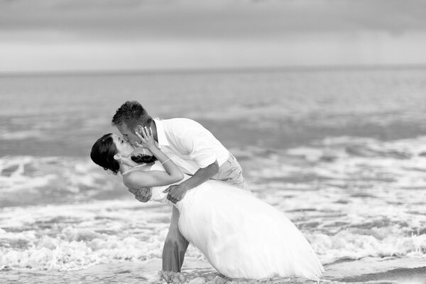 Ein Mann und eine Frau bei einer Hochzeit küssen sich am Ufer