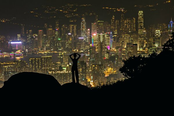 Silhouette eines Mädchens auf dem Hintergrund der Nachtstadt