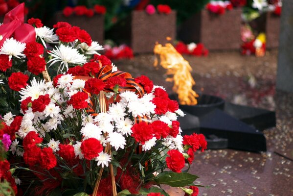 Ewiges Feuer mit einem Korb voller Blumen im Vordergrund
