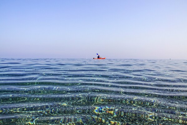 Mann im Kanu schwimmt im Meer