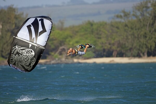 Surfer fliegt über das Meer und hält sich an einem Fallschirm fest