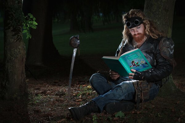 Ein langhaariger Mann mit Bart liest ein Märchenbuch im Wald