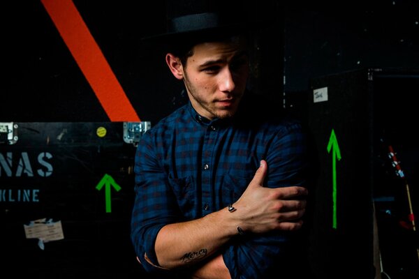 Nick Jonas umarmt sich mit den Armen und schaut nach links