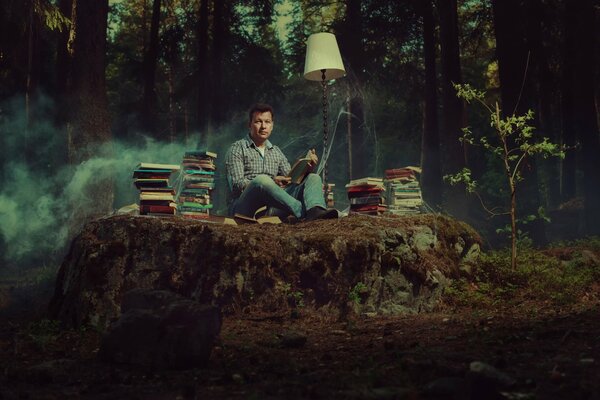 Ein Buchliebhaber sitzt mitten im Wald mit Büchern und einer Lampe