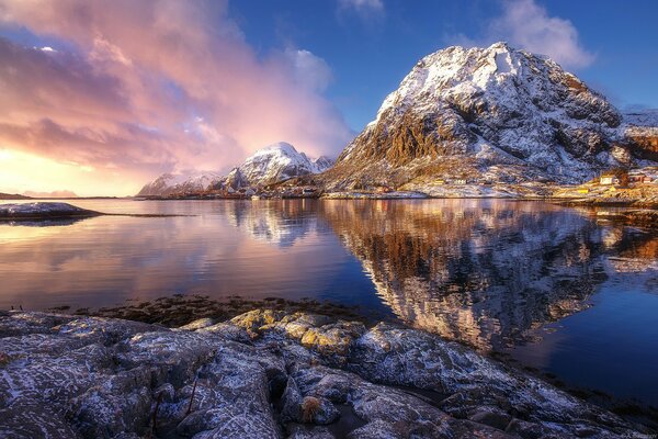 Der rosa Sonnenuntergang und die schneebedeckten Felsen spiegeln sich im blauen Wasser wider