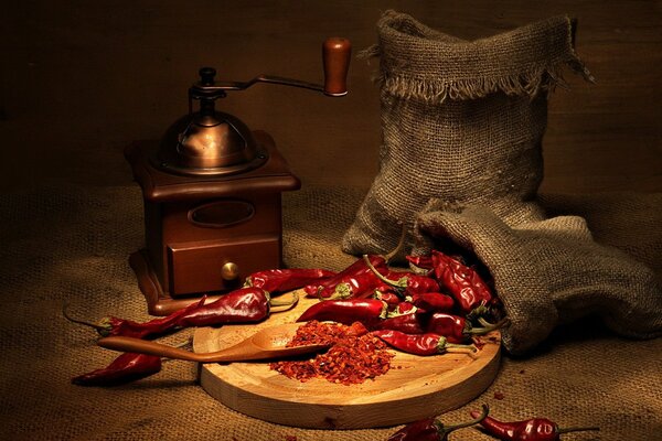 Auf einem Tablett mit roter Chilischote, aus einem Sack verstreut, ganz und in der Nähe bereits gemahlen