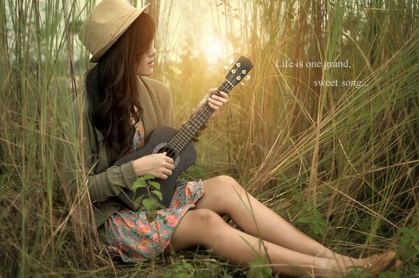 Die Gitarre in den Händen eines Mädchens in der Natur