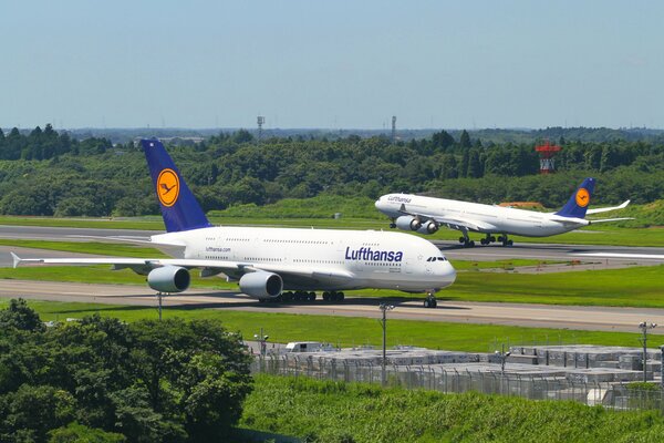 Zwei weiße Flugzeuge stehen auf der Startbahn